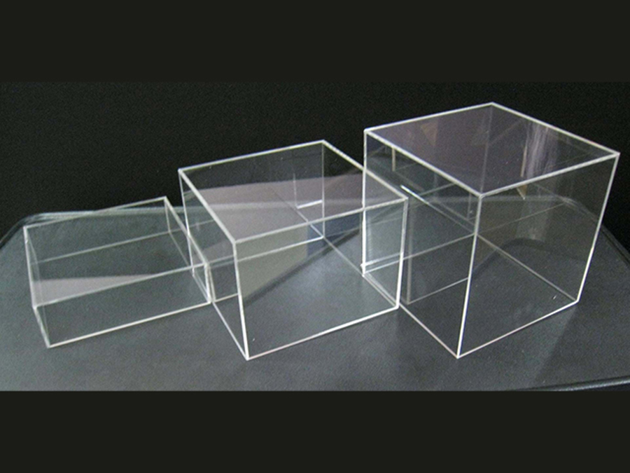 Three clear acrylic box risers in graduated sizes, lined up from smallest to largest on a dark surface