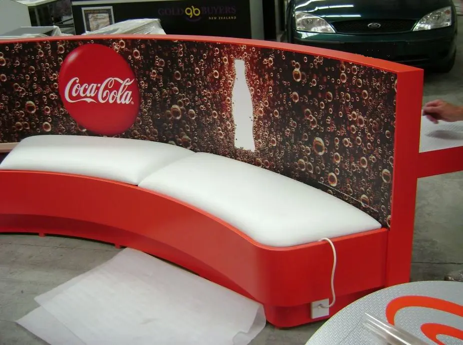Red and white Coca-Cola curved bench with long white seat cushions and a bubble graphic
