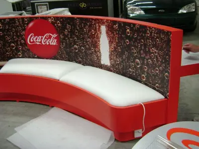 Red and white Coca-Cola curved bench with long white seat cushions and a bubble graphic
