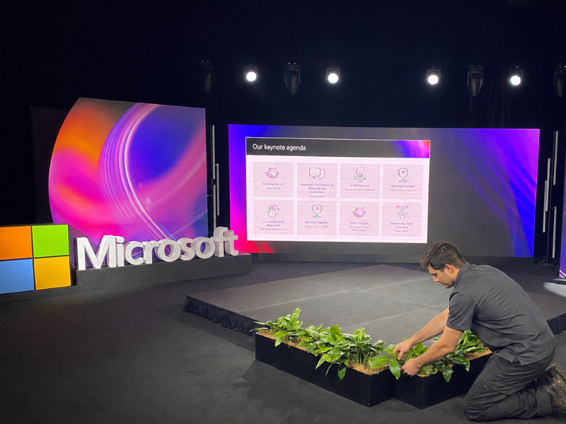Microsoft keynote set being built, with a crew member planting the stage garden bed
