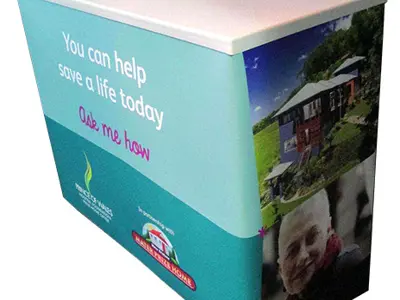 Teal Prince of Wales charity counter with a white top and photos on its side