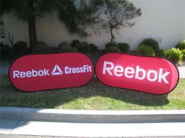 Pair of red Reebok and Reebok CrossFit oval banners standing on grass