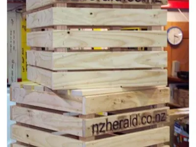Slatted timber crates with nzherald.co.nz burnt in, stacked into a tall column