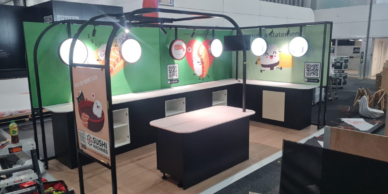 Sushi Machines stand from the aisle, showing the lighting rig and preparation benches