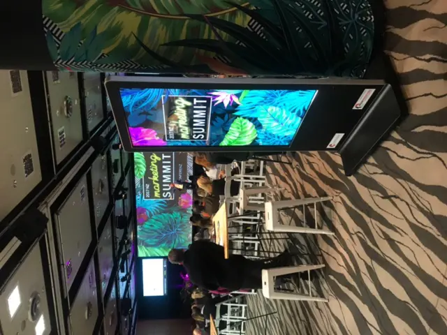 Portrait screen totem at NZ Marketing Summit 2017 showing tropical artwork matching the stage