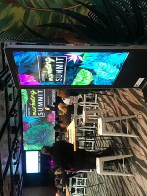 Portrait screen totem at NZ Marketing Summit 2017 showing tropical artwork matching the stage