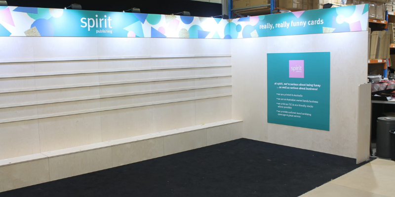 Spirit Publishing stand shell with illuminated header and empty shelving before merchandising