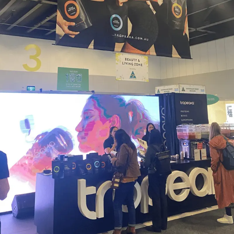 Tropeaka counter with 3D letters and smoothie samples in front of an LED screen wall
