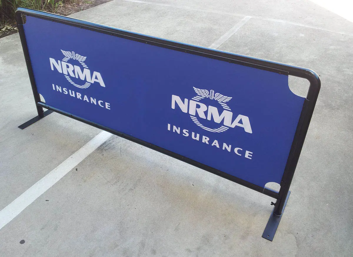 NRMA Insurance barrier with a blue printed panel on a rounded steel frame outdoors