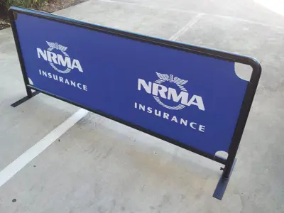 NRMA Insurance barrier with a blue printed panel on a rounded steel frame outdoors