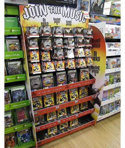 Guitar Hero 5 'Join the Music' stand with hanging packs above shelves of boxed games