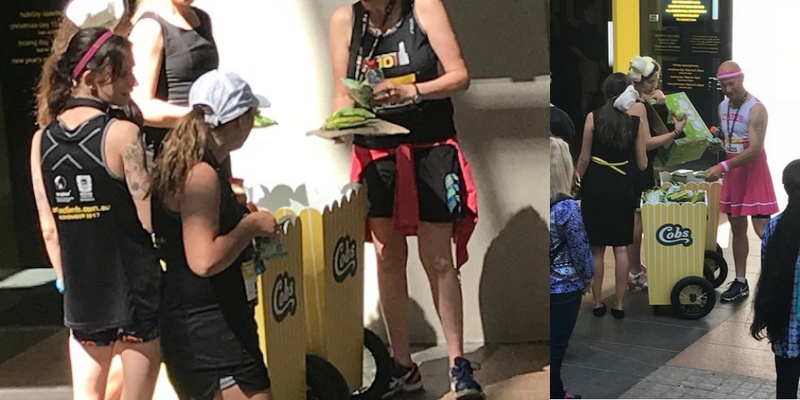 Staff handing out COBS popcorn samples from the branded trolley at an outdoor event