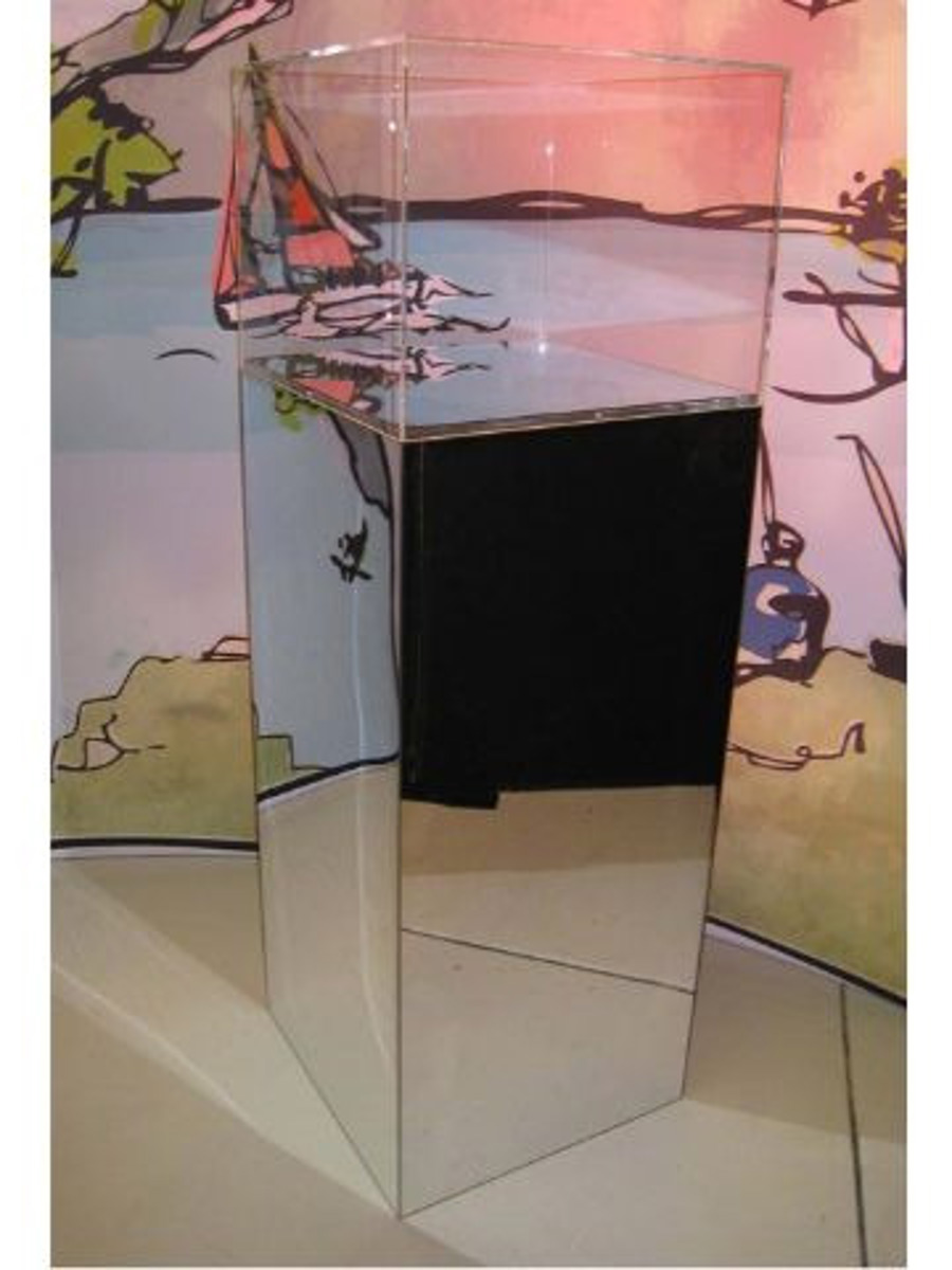 Tall mirror-finish plinth topped with an empty clear acrylic display case, set against an illustrated wall graphic