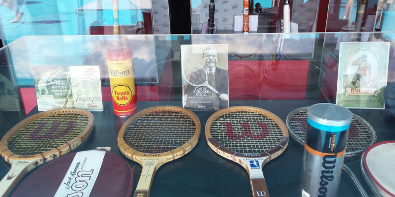 Vintage Wilson tennis racquets and memorabilia inside a clear display case