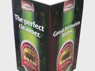 Three Oaks Cider demo table wrapped with a bottle image and a clear white top
