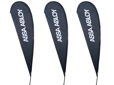 Three dark ASSA ABLOY teardrop flags with large white vertical lettering