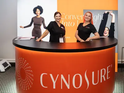Cynosure counter with an orange wrap and black top in front of a printed backdrop