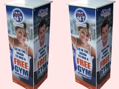 Plus Fitness 24/7 entry plinths with member portraits and a slot in the white top