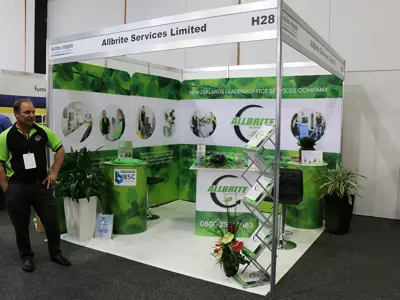 Allbrite Services corner shell scheme stand with leaf artwork, staff photos and a branded counter