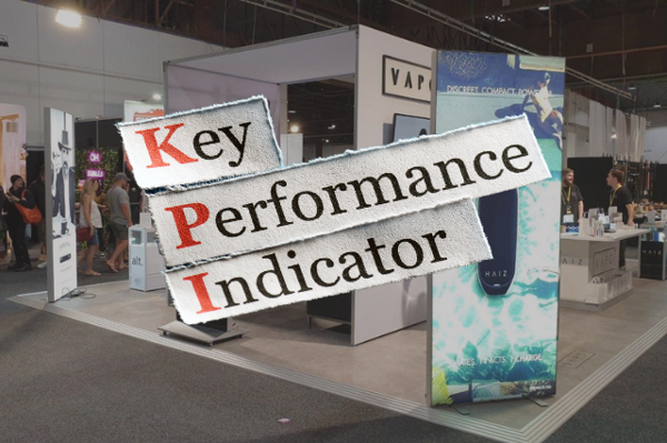 The words Key Performance Indicator on cut-out paper labels, over a blurred exhibition stand