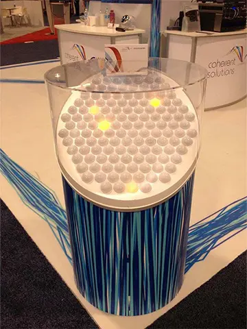 White spheres, some lit yellow, under a clear dome on the Coherent Solutions stand