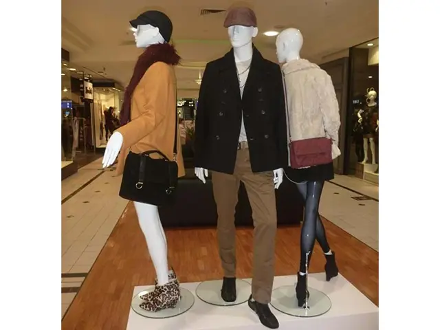 Three mannequins on clear acrylic bases atop a low white platform in a walkway