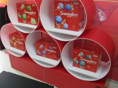 Red cluster of five round openings, each holding a Snugglers nappy pack on a plinth