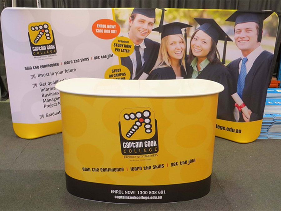 Curved pop-up counter with a yellow printed wrap in front of a matching printed fabric backdrop wall