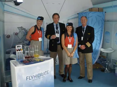 Brand ambassadors dressed as pilots and flight attendants behind a FlyHidrate counter with drink jugs