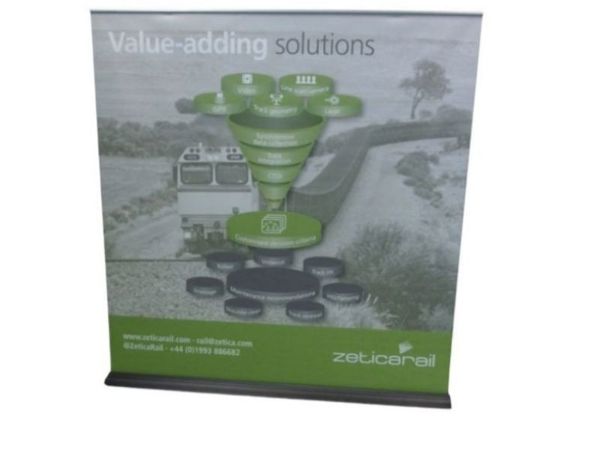 Extra-wide pull-up banner printed with a green and grey infographic, standing flat on a black base