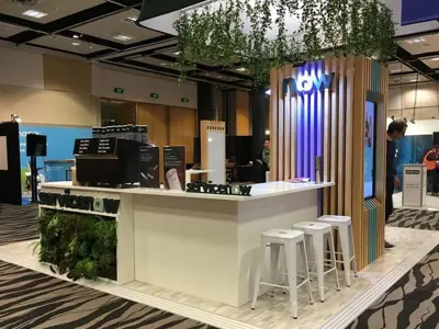 ServiceNow coffee bar with white stools, a planted end panel and a lit timber-slat tower