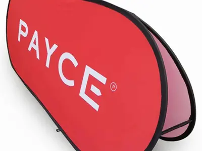 Red PAYCE pop-up A-frame banner standing low on its own flexible frame
