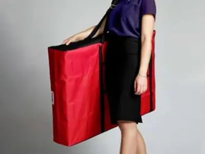 Slim red padded carry bag with a shoulder strap holding a portable demo table