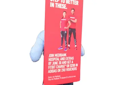 Promoter carrying a tall printed Medibank board strapped over the shoulders, rising above head height