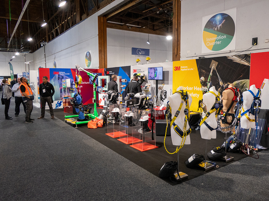 3M worker health and safety stand at an exhibition, with safety harnesses on mannequins and helmets on acrylic plinths
