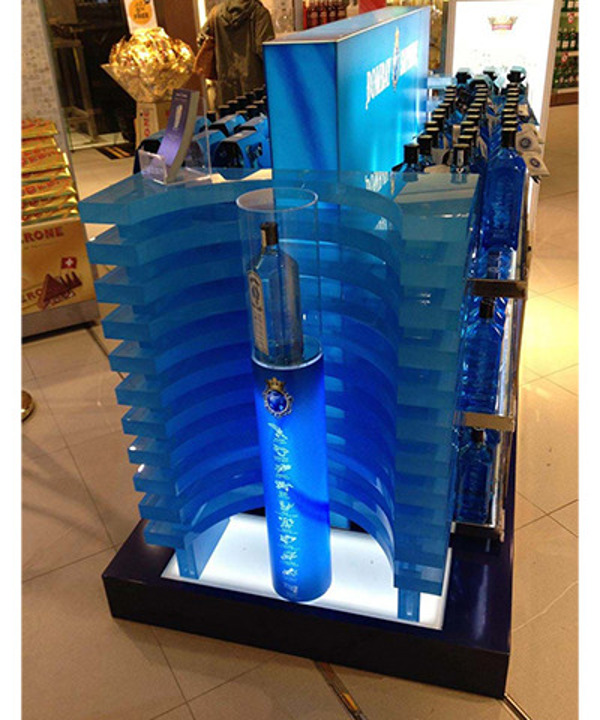Frosted blue acrylic retail display with a lit base and a clear acrylic tube showcasing a spirits bottle