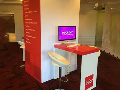 Infor Day demo desk with a computer beside a tall red and white industry tower