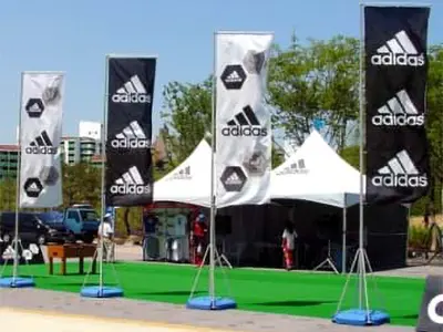 Black and white Adidas flags on weighted bases in front of peaked marquees