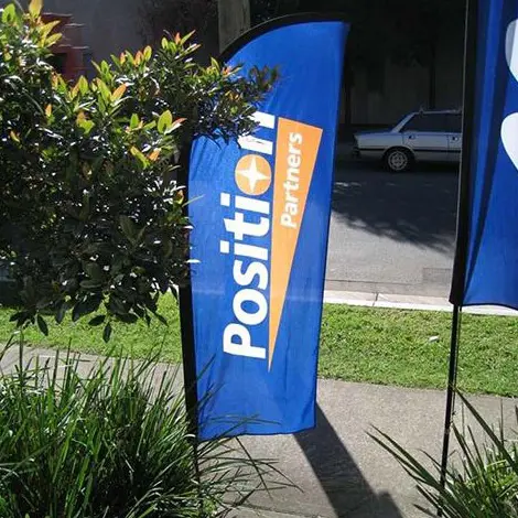 Blue Position Partners bow flag with an orange accent beside a footpath and garden