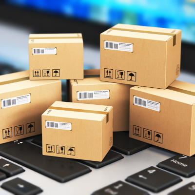 Stack of cardboard shipping boxes sitting on a laptop keyboard