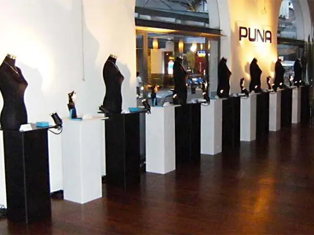 Long row of alternating black and white plinths with busts and lamps lighting PUNA jewellery