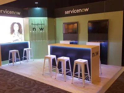 ServiceNow stand with blue-edged bar-height counters, stools and wall screens on a timber-look floor