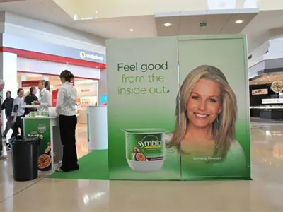 Tall green Symbio printed wall beside a branded sampling counter on green floor covering
