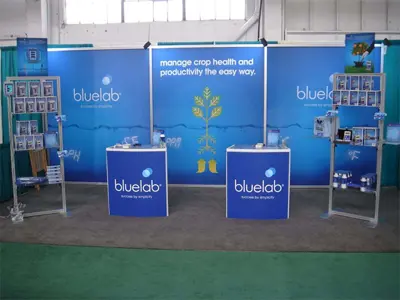 Bluelab stand with a plant-and-root graphic, two branded counters and end shelving racks