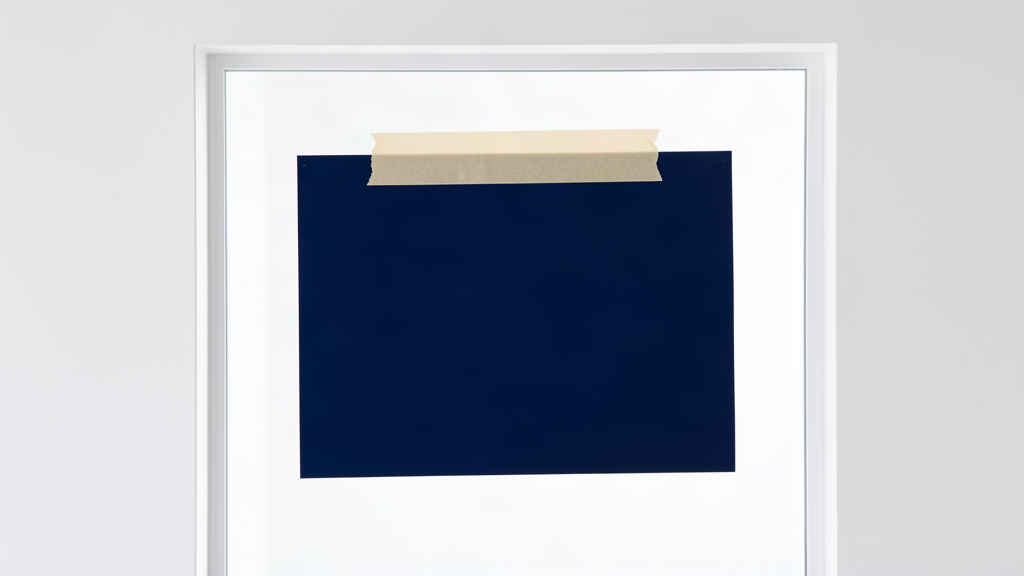 Window decal taped to the glass with a masking tape hinge along the top