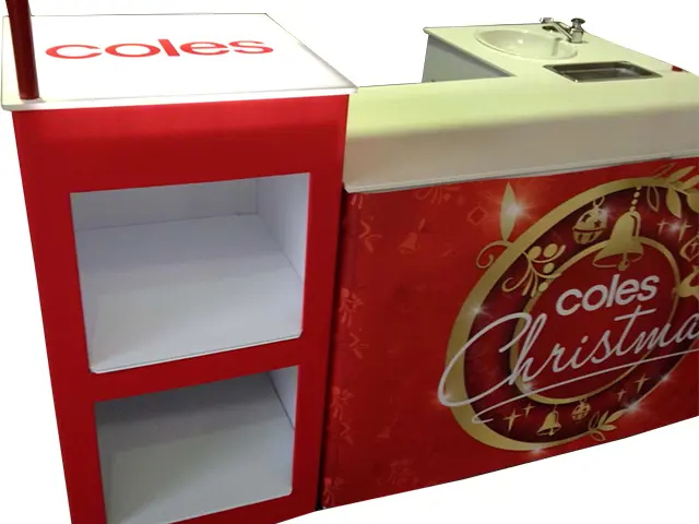 Coles Christmas demo table with a basin and a red side unit with open shelves