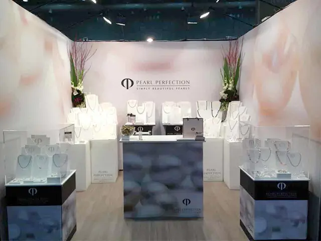 Pearl jewellery stand with glass cases, necklace busts and a central counter before pale walls