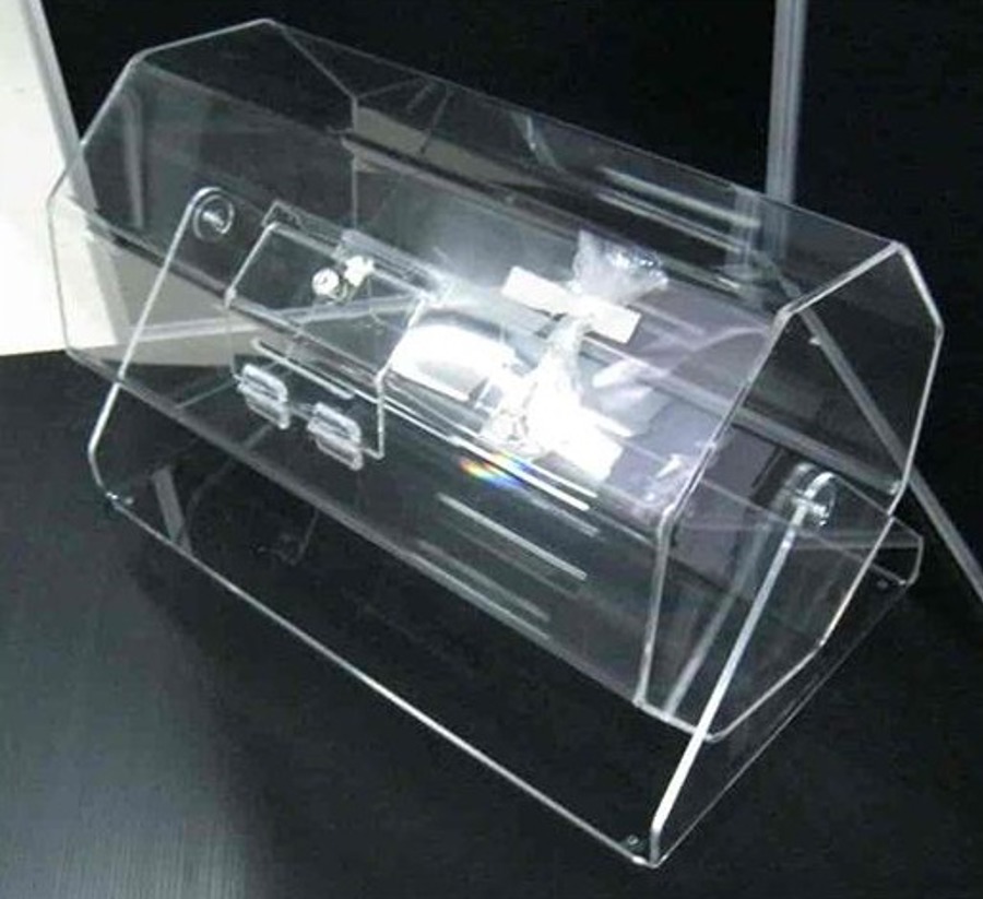Clear acrylic counter-top raffle barrel with a hinged door, on a dark surface