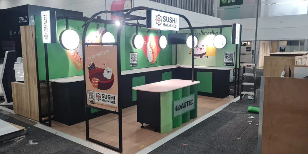 Corner view of the Sushi Machines stand with branded header and bench units