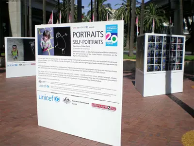 UNICEF outdoor panels pairing children's photos with their drawings beside a cube photo grid